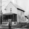 Carlyle B. Haynes standing in front of an old home in Battle Creek Village