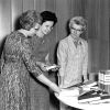 [Mary Jane Mitchell of the James White Library giving 22 books to Niles librarian Anne Frese, while Gladys Kneeshaw looks on]