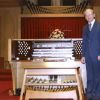 C. Warren Becker standing by new organ in Pioneer Memorial Church