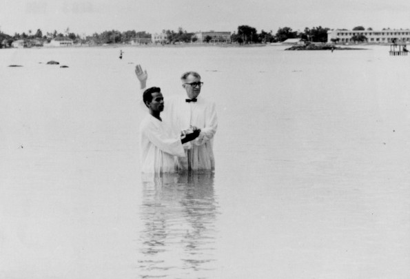 Andrews University Theological Seminary student, Clarence Goertzen, baptizes a convert in a new area in Ceylon in a ninety-percent Buddist village