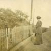 [Unknown woman reading by a fence]