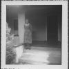Bessie DeGraw standing on the porch of a house in the summer of 1957