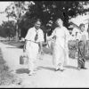 [Sallie Sutherland and children with canning supplies walking along a road, possibly at Madison College]