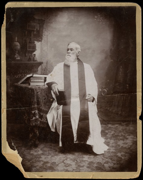 Joshua V. Himes in regalia, seated with books
