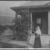Nellie Simpson holding Winea in front of house