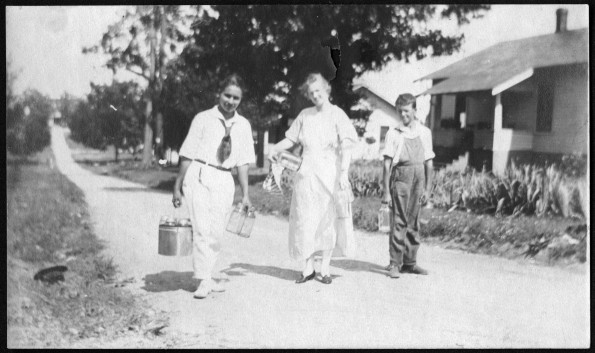 [Sallie Sutherland and children with canning supplies walking along a road, possibly at Madison College]
