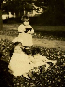 Young girls sitting and standing in the fallen leaves.