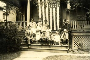 Family sitting on steps with American flag draped behind them.