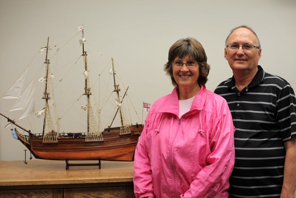 A woman and man standing with a model of a sailing vessel.