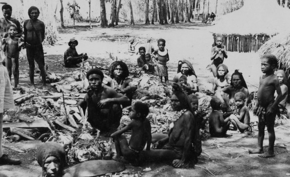 A common scene at the village of Kabiufa, Central New Guinea. The natives have just slaughtered a pig and are preparing for a feast.