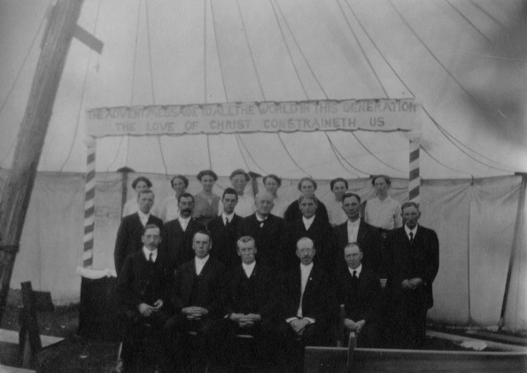 Group of men and women, possibly part of the camp meeting leadership team in the main tent at Michigan camp meeting, possibly in the 1920s