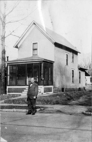 Carlyle B. Haynes standing in front of an old home in Battle Creek Village