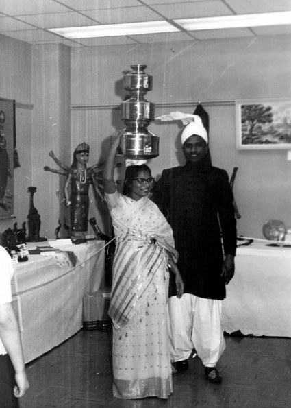 Justin Singh and wife from India demonstrate carrying pot on your head as part of the World Mission Exhibit at Andrews University Feb. 21 thru Mar. 1, 1967
