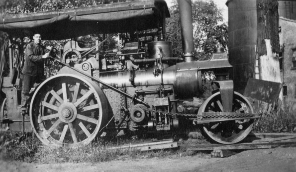 Unknown man and a very large tractor from the 1920's era or earlier