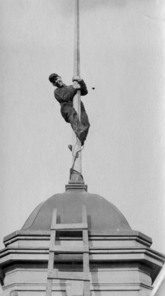 Unknown man climbing a flagpole