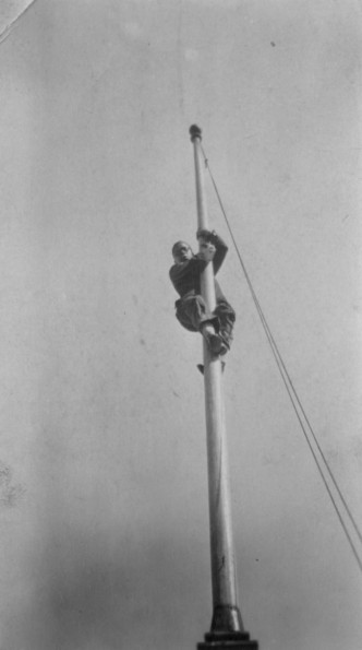 Unknown man climbing a flagpole