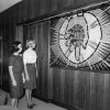 [Two students admire Ann Steinweg's mural of Christ's hand holding the symbol of Andrews University on display at the Andrews University board room]