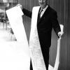 [Leonard Hill standing with the 22-foot length invoice for the 1,194 magazines and periodicals to which the James White Library subscribes]
