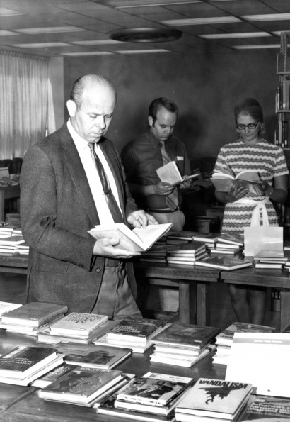 [Richard Powell, Larry I. Bergstrom, and Donna Stout looking over the book display in the James White Library]