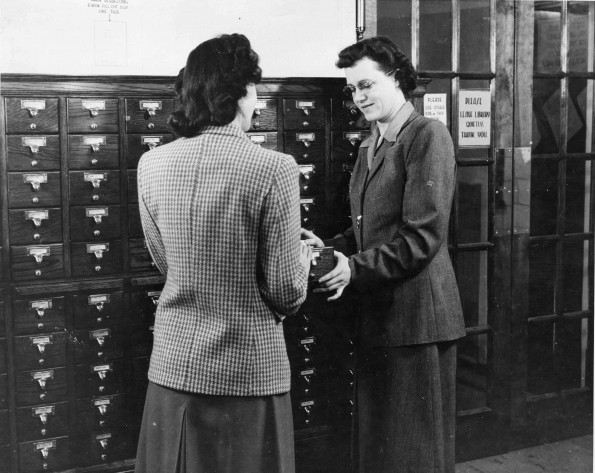[Library staff at Emmanuel Missionary College library assisting student with looking up a book]