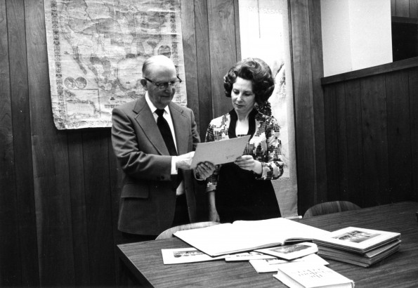 [Emmett Vande Vere and Louise Dederen reviewing historical pictures in the Heritage Room at Andrews University]