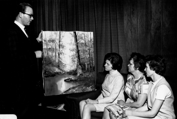 [Charles Brown showing the Art and Craft Show Committee one of the paintings to be displayed]