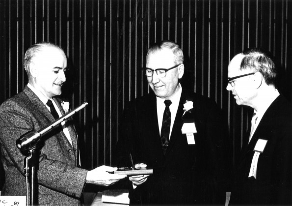 Owen A. Blake receives a desk pen holder from F. E. J. Harder