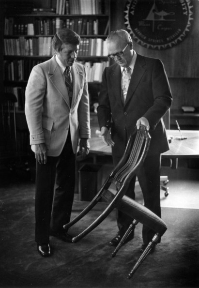 [Donald Prior and H. H. Hill with a chair designed by John Harvey Kellogg]
