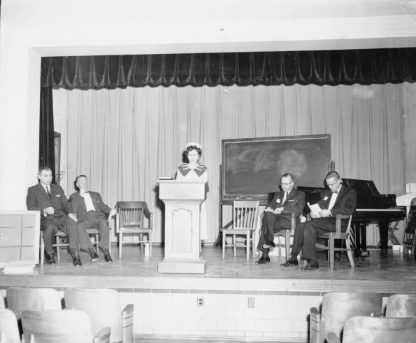 Andrews University president, Floyd O. Rittenhouse, and vice president, Fabien A. Meier, listen to a speaker at the alumni Homecoming ceremony