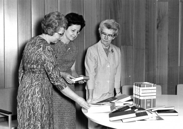 [Mary Jane Mitchell of the James White Library giving 22 books to Niles librarian Anne Frese, while Gladys Kneeshaw looks on]