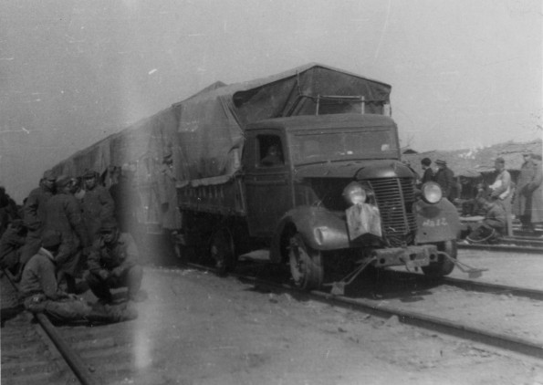 A truck converted to run on a railroad track pulls several train cars