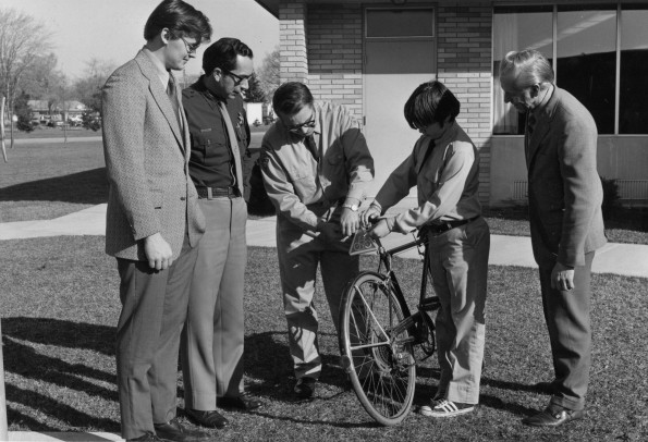 [Dale Howell helping Eddie Huddleston put a reflective safety triangle on his bicycle]