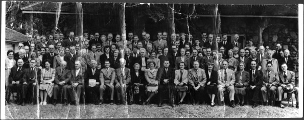 Group of unknown people posed in front of a stone building