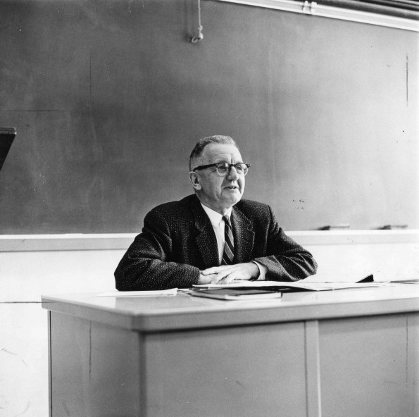 Edward Heppenstall at the teacher's desk in a classroom
