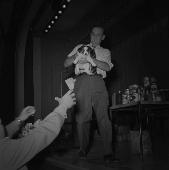 [Handing a puppy to a man in the Johnson Gymnasium Auditorium]