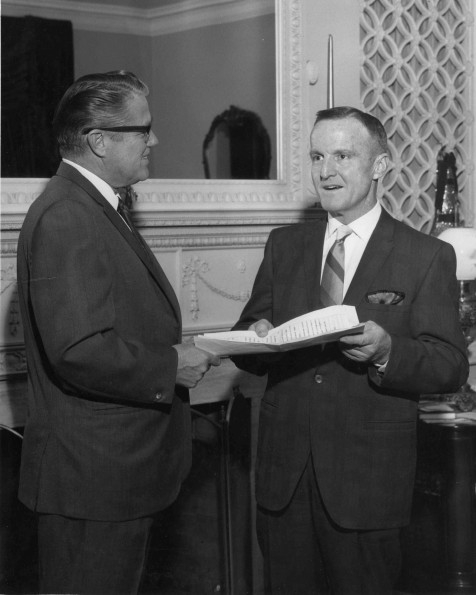 Dr. Howard O. Stocker, Andrews University alumnus, gives a gift to John Osborne who is an officer of the University