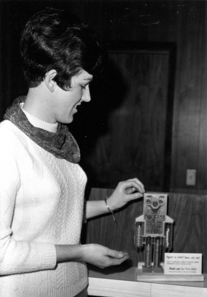 [Verlyne Bartlett puts money into a fundraising bank for Christian Youth Action]