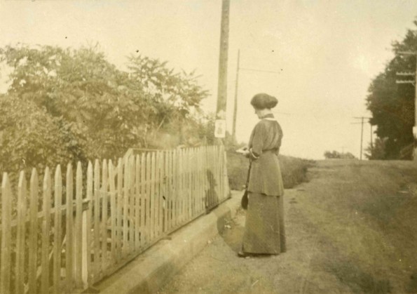 [Unknown woman reading by a fence]