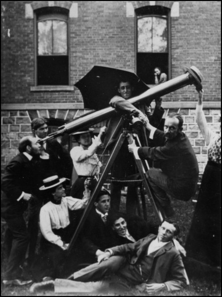 Battle Creek College astronomy class clowning around with large telescope