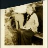 Nellie Druillard sitting on the running board of an automobile, with a man next to her, probably E. A. Sutherland