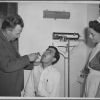 Joseph Sutherland examines a patient while an unknown nurse looks on