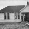 Three unknown men standing in front of an unknown building at Madison College