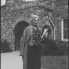 M. Bessie DeGraw in front of a building at Madison College, holding books