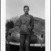 Young man in suit standing in front of a car, possibly Robert Sutherland