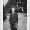Edward A. Sutherland standing on lawn with hat in hand