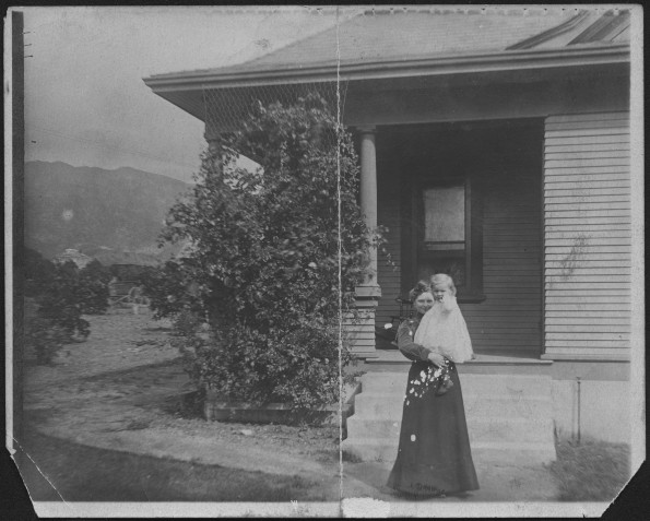 Nellie Simpson holding Winea in front of house