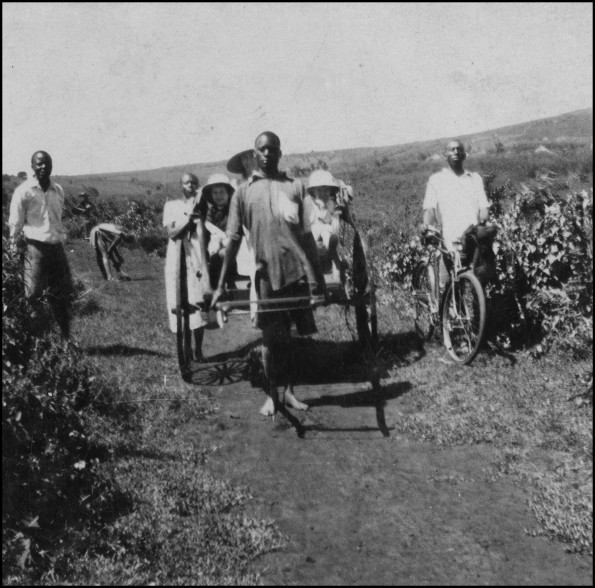 Myrna Beavon with her two sons Fred and Harold riding in a cart surrounded by natives
