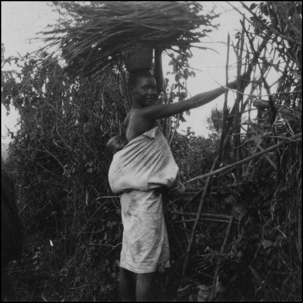 Kisii woman with baby and a load of wood on her head